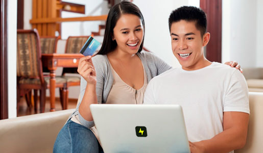 Person sitting with lady doing some work on laptop & lady holding credit card in hand
